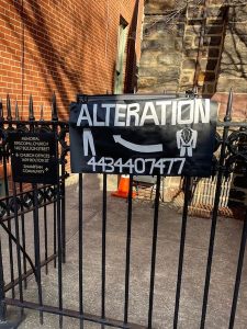 alterations sign on a fence outside of a churge